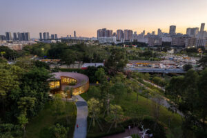 High-angle view of the Serpentine Bookhouse's circular roof and its integration into the surrounding park landscape and river pathway