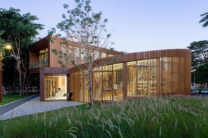 Full exterior view of the Serpentine Bookhouse at night, highlighting the floor-to-ceiling windows and the spiral sculpture-like form