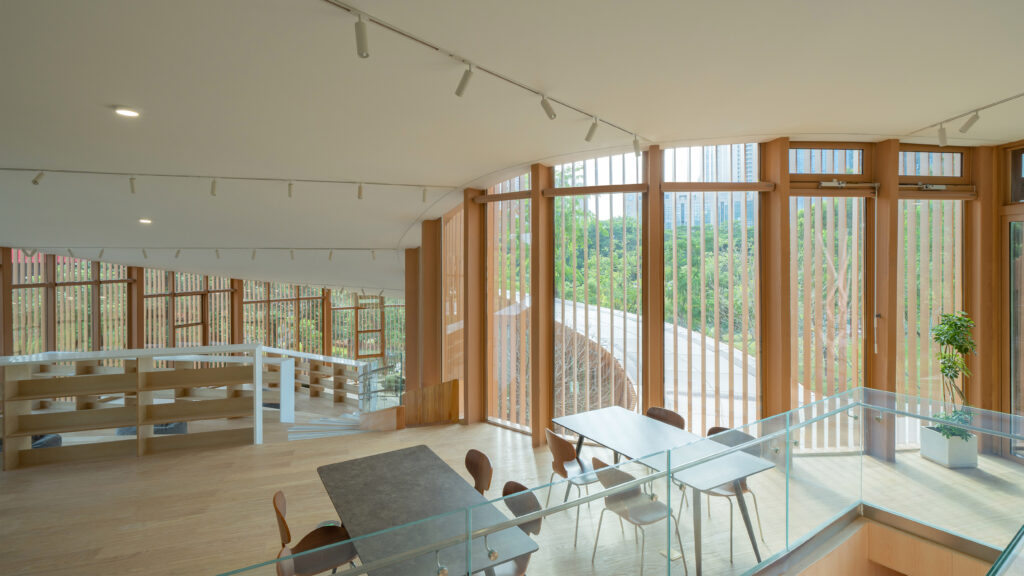 Interior shot of the reading room featuring floor-to-ceiling windows that provide a panoramic view of the Dasha River park landscape