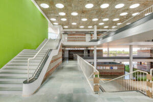 Interior view showing the central courtyard with a green feature wall, staircase, and ceiling punctures for natural light.
