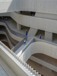 Looking down into a courtyard at the layered, winding corridors protected by wavy perforated metal railings