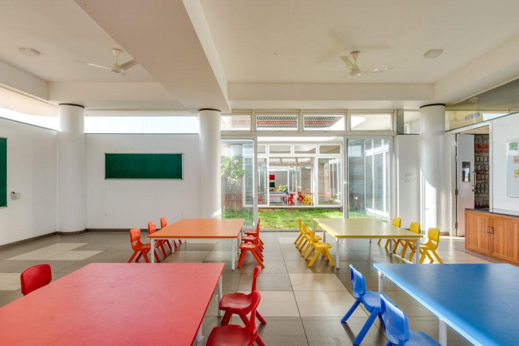 Indoor classroom for kindergarten featuring colorful furniture and large glass doors opening to a private garden.
