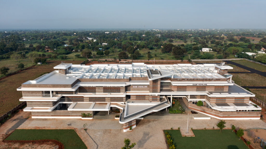 High-angle aerial view of the entire Rane Vidyalaya campus nestled in the rural landscape of Theerampalayam.
