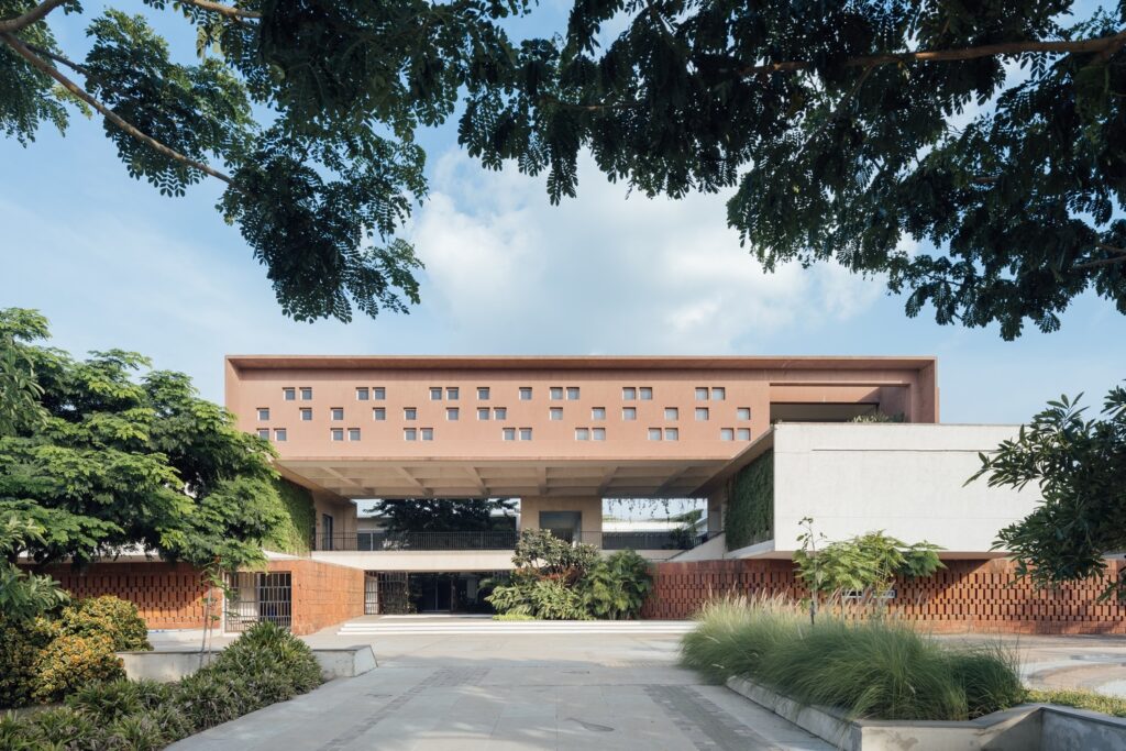 A front view of the school showing the terracotta-coloured Bella stone Jalli on the ground floor and the white upper-floor massing with rhythmic window openings
