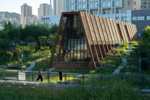 A side view of the tea house's rhythmic wooden facade, appearing as a natural extension of the surrounding park greenery