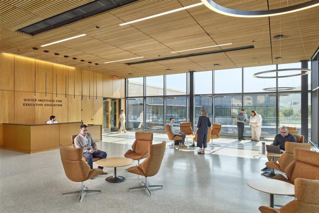 Students walking along a bright mezzanine lounge and modern staircase designed to facilitate informal meetings and study sessions