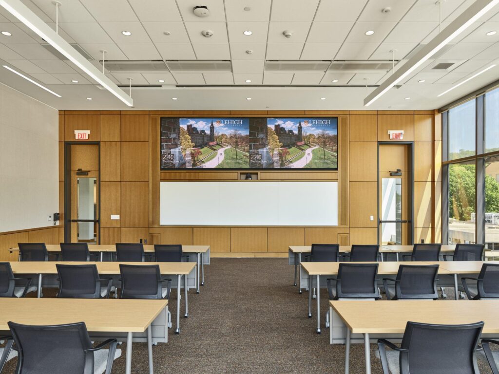 A technology-forward classroom equipped with advanced sound systems, integrated monitors, and desks for hybrid learning
