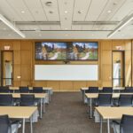 A technology-forward classroom equipped with advanced sound systems, integrated monitors, and desks for hybrid learning