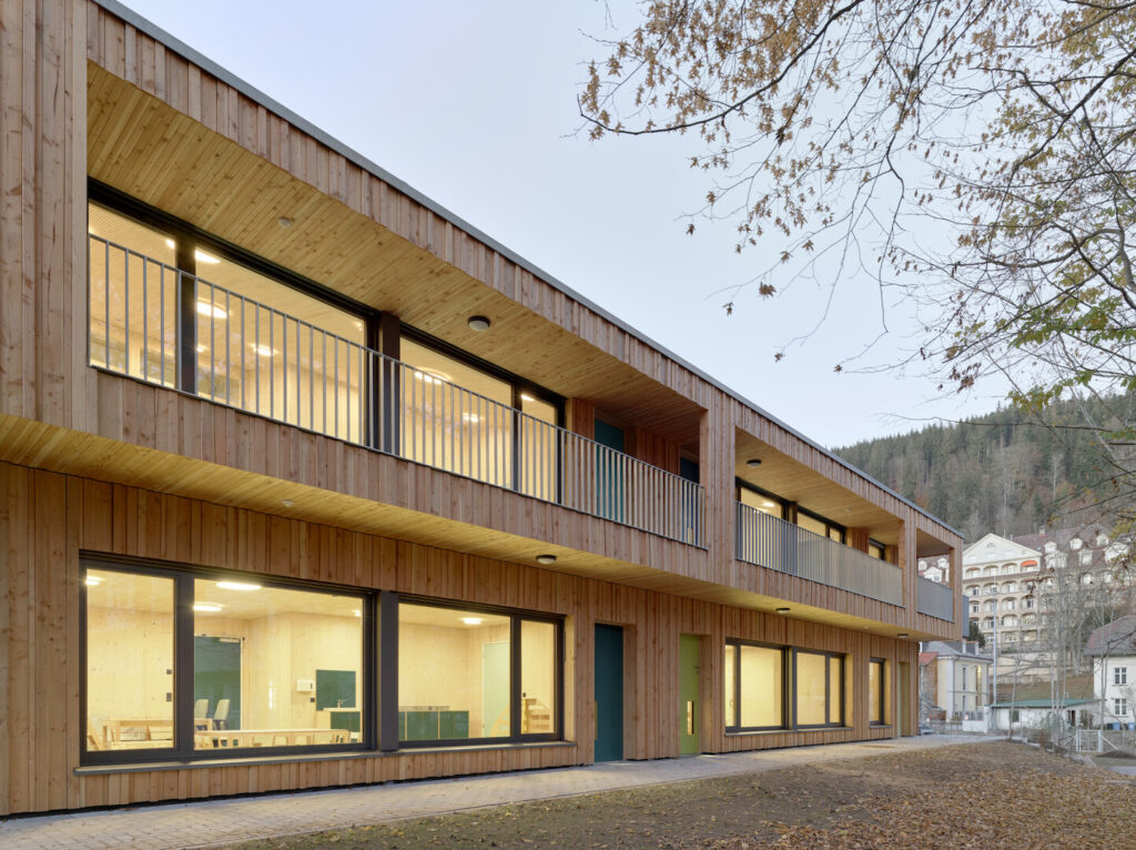 A long view of the kindergarten extension showing the rhythmic wood siding and the building’s integration into the Black Forest urban surroundings