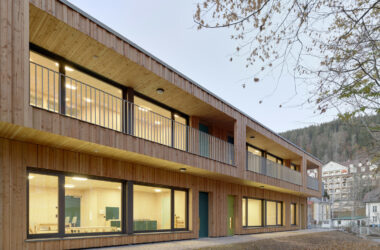 A long view of the kindergarten extension showing the rhythmic wood siding and the building’s integration into the Black Forest urban surroundings