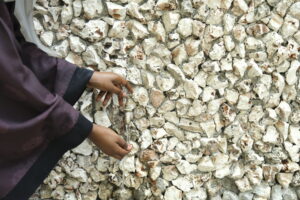 Close-up of hands using a metal tap mounted on a textured stone wall, part of the library’s environmental strategy and cultural depth
