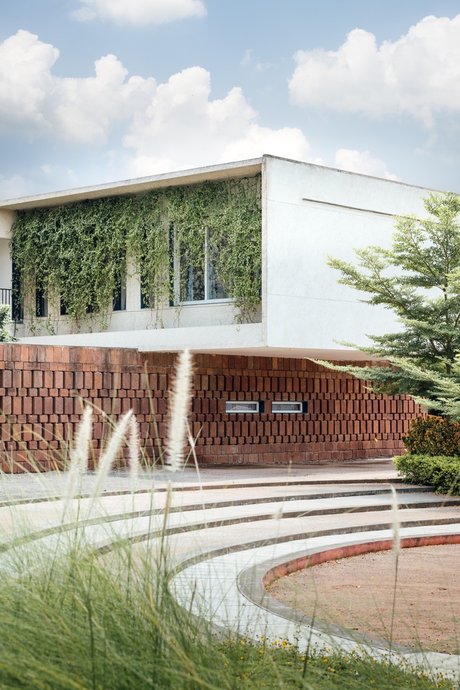 The school building seen from a distance with native grasses and curved pathways in the foreground, blending the architecture with nature
