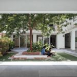 Students utilizing a shaded courtyard space for informal study, surrounded by lush green pockets and trees
