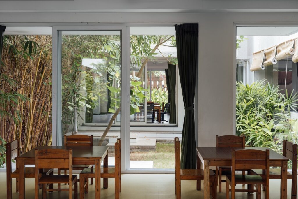 View from a wood-furnished classroom through glass doors into its own private, open-to-sky courtyard