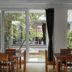 View from a wood-furnished classroom through glass doors into its own private, open-to-sky courtyard