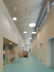 A bright interior corridor showcasing the high, sloping cross-laminated timber ceilings and natural wood walls