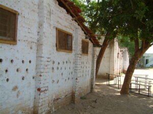 Close-up of a white-painted local brick wall with circular perforations designed for simplified passive cooling at the school