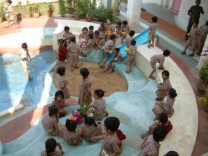 Overhead view of a circular, multi-level play area in the school courtyard featuring colourful china mosaic patterned flooring and slides