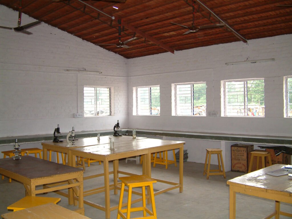 A brightly lit science laboratory at the school with microscopes on wooden tables and large windows providing natural illumination