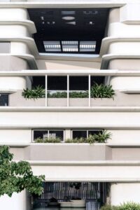 A close-up shot of the building facade showing how the horizontal ribs function as railings and convert into built-in planters near window locations