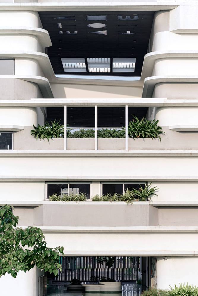 A close-up shot of the building facade showing how the horizontal ribs function as railings and convert into built-in planters near window locations