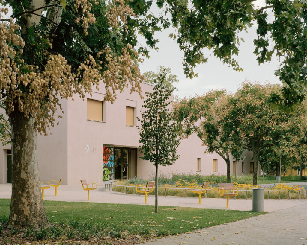 View of the kindergarten entrance area featuring the fire-enamel art piece and yellow outdoor furniture inspired by children’s building blocks