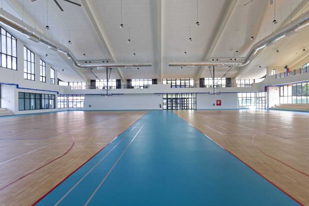 Eye-level view of the expansive indoor gymnasium floor at Vientiane International School, a regenerative space designed to support physical health and community-focused activities
