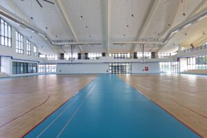 Eye-level view of the expansive indoor gymnasium floor at Vientiane International School, a regenerative space designed to support physical health and community-focused activities