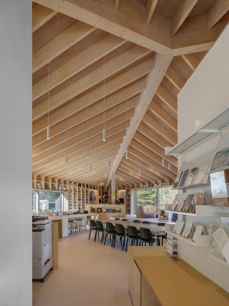 Interior view showing the heavy timber beams and columns of the triangular roof, with a long study table and bookshelves.