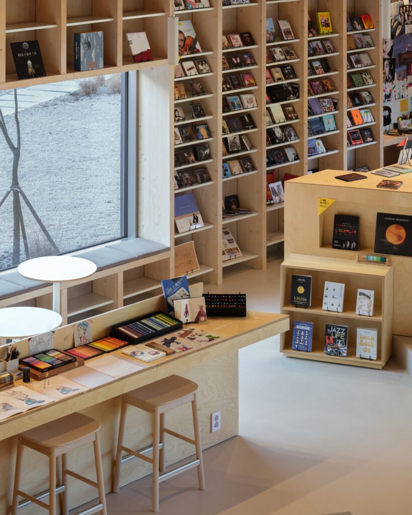 Close-up of wooden library shelves and a table equipped with art supplies and stools.