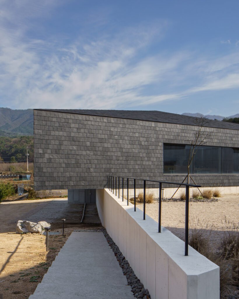 A view of the raised library structure and a concrete path leading toward the lower level.