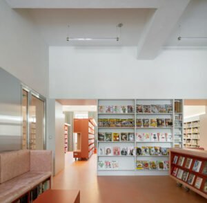 A tall, custom-built pink upholstered mobile reading booth on wheels, designed as a cozy, private reading nook for young library visitors.