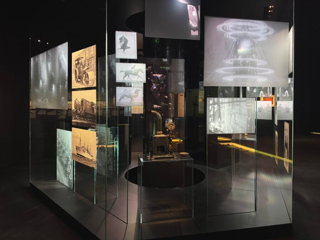 Glass display case featuring vintage photos and sketches of steam trains, draft animals, and historical vehicles.