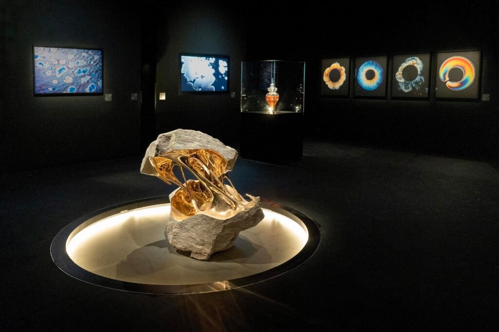 Abstract sculpture of a split white stone bridged by a flowing, polished golden liquid-metal shape.