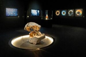 Abstract sculpture of a split white stone bridged by a flowing, polished golden liquid-metal shape.